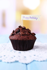Chocolate muffin on wooden table, on bright background