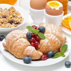 breakfast with croissants, eggs, muesli, fresh berries, oranges