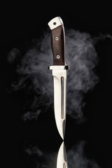 Hunting knife with smoke on a black background