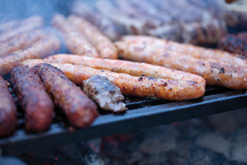  pork and beef sausages cooking over the hot coals on a barbecue