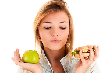 beautiful woman choosing between apple and hamburger
