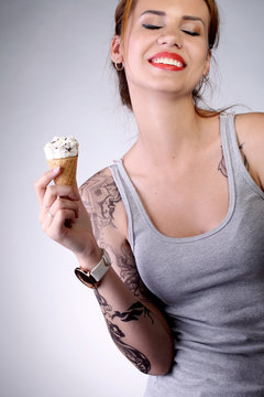 Молодая девушка с улыбкой держит рожок мороженого в руке
