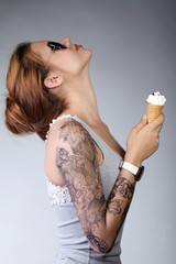 Молодая девушка в профиль на сером фоне с рожком мороженого