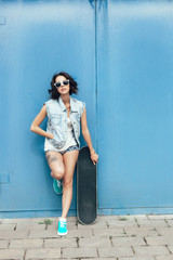 Fototapeta premium Young brunette woman posing with skateboard