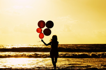 beautiful woman with colorful balloons on seaside