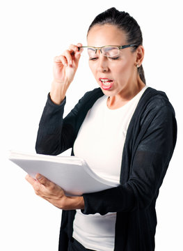 Joven mujer administrativa en fondo blanco con cara de sorpresa y gafas leyendo documentos que lleva en la mano. Concepto de negocios en la oficina.