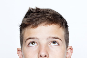 Close up portrait of boy looking up against gray background