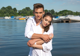 Fototapeta premium Man hugging woman near a water in front of boats