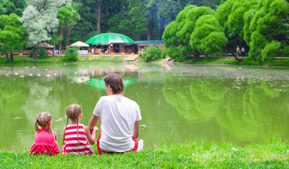 Happy father and little cute daughers near the lake