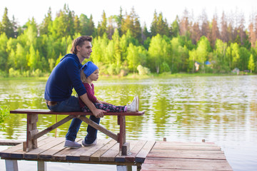 Young father and little adorable girl fishing on the river