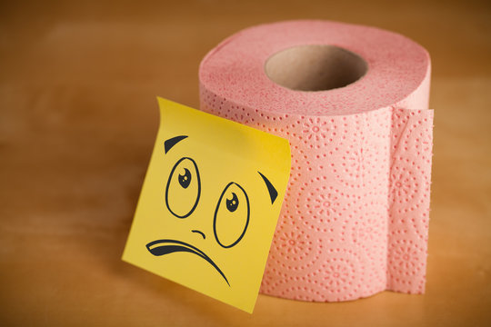 Post-it note with smiley face sticked on toilet paper