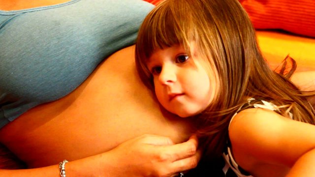 bambina manda bacio e sente la pancia della mamma incinta