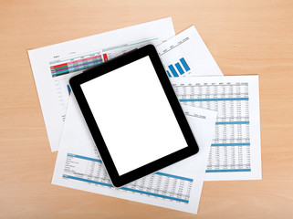 Tablet with blank screen over papers with numbers and charts