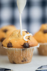 Icing frosting being put onto home made chocolate chip muffins