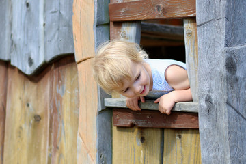 Cute little girl playing in wooden house at playground