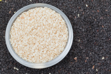 White seed sesame in the cup on the black seed sesame background