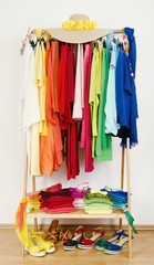 Wardrobe with summer clothes and shoes arranged by colors.