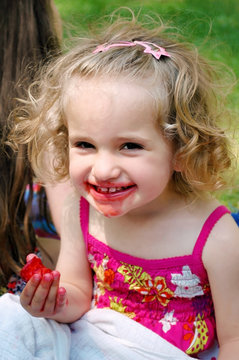 Girl in a summer eating fresh strawberries.