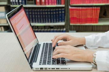 Teenage girl using laptop in library