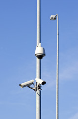 Fototapeta na wymiar two security cameras on electric post and lamp