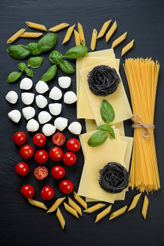 Various italian ingredients over black wooden background