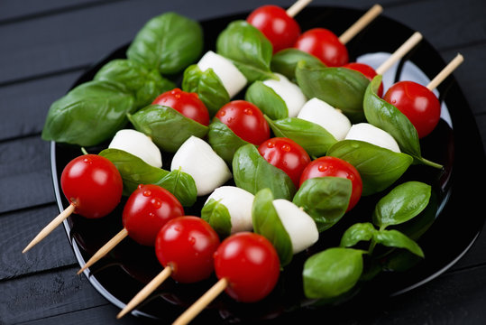 Kebabs with cherry tomatoes, green basil and mozzarella balls