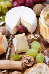 Camembert, glass of white wine, grapes and fresh baguette