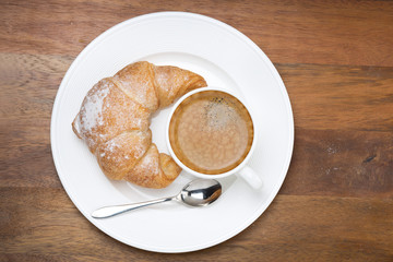 croissants and cup of coffee on a plate on wooden background