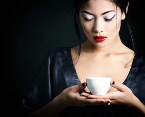 Young beautiful asian woman and tea ceremony, studio shot over b