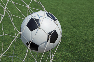 Fototapeta na wymiar Soccer ball in goal and green grass field