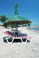 Relaxing sunbeds on the beach under straw umbrella