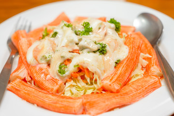 salad of crab stick with sauce mushroom on white plate