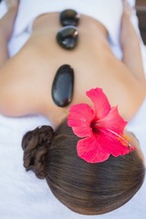 Obraz na płótnie Canvas Relaxed brunette lying on towel having a hot stone massage