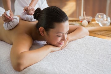 Obraz na płótnie Canvas Content brunette enjoying a herbal compress massage
