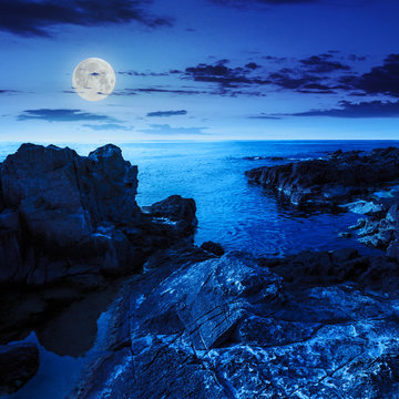 calm sea wave touches boulders at night