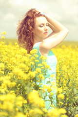 Naklejka na ściany i meble Beautiful young woman in flower field