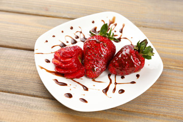 Red ripe strawberries with chocolate on wooden table
