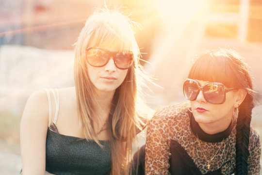 Two female in sunglasses backlit by sunset