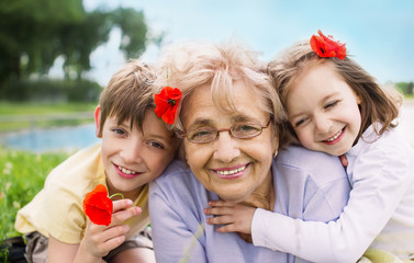 happy grandmother with grandchildren outdoors - obrazy, fototapety, plakaty