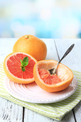Ripe grapefruits on plate, on color wooden background