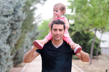 Little girl walking on the shoulders of her father