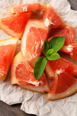 Ripe chopped grapefruit with mint leaves on wooden background