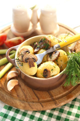 Young boiled potatoes in pan with vegetables on table in
