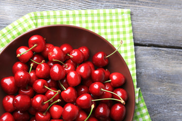 Sweet cherries  on plate on wooden background