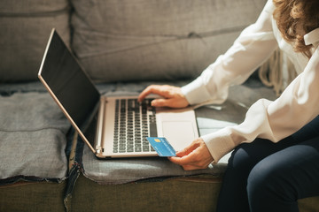 Closeup on young woman with credit card using laptop 