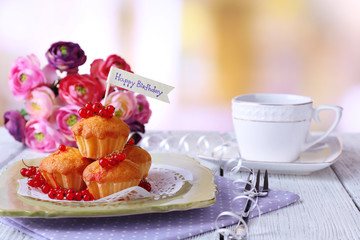 Tasty muffins on plate, on wooden table, on bright background