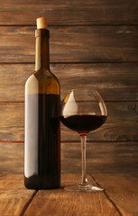 Bottles of wine with glass on wooden background