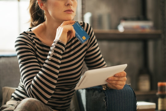 Closeup on thoughtful young woman with credit card and tablet pc