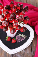 Strawberry in chocolate on skewers in cup on table close-up
