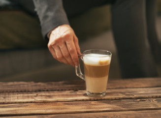 Closeup on business woman taking coffee latte from coffee table